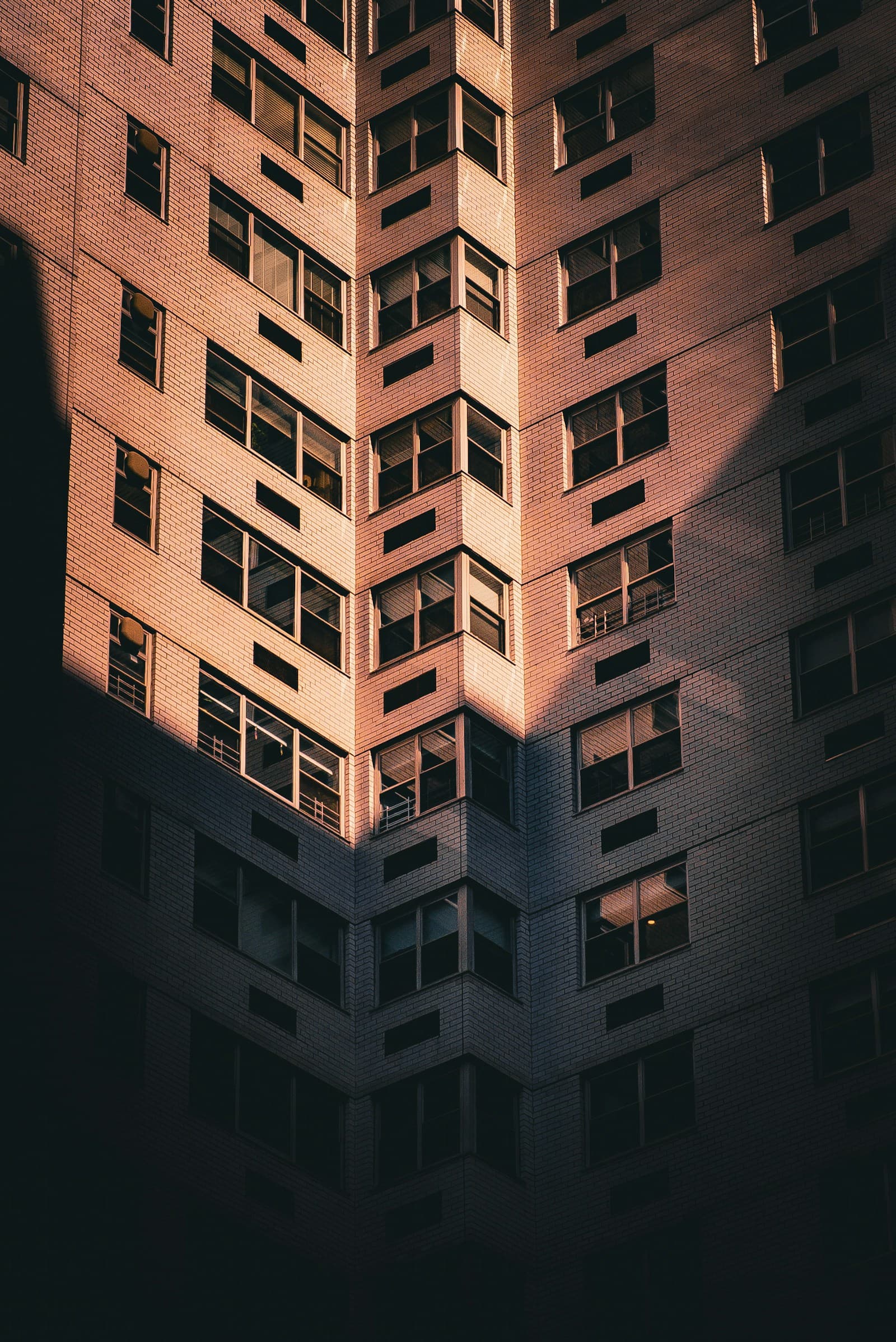 The brick facade of an apartment building in strong sunlight and shadow